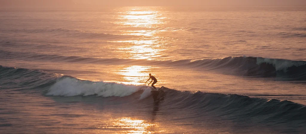 A surfer catching waves during a beautiful sunset at Saltburn